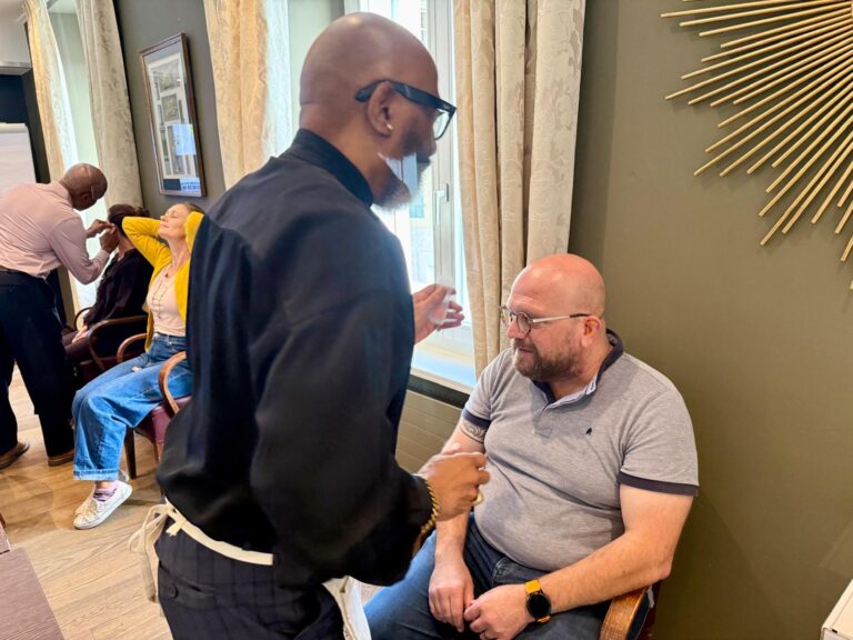 A trainer treating a participant’s ear while others receive treatment in the background