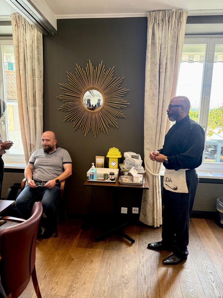 A trainer and a participant in a treatment room with a sunburst mirror