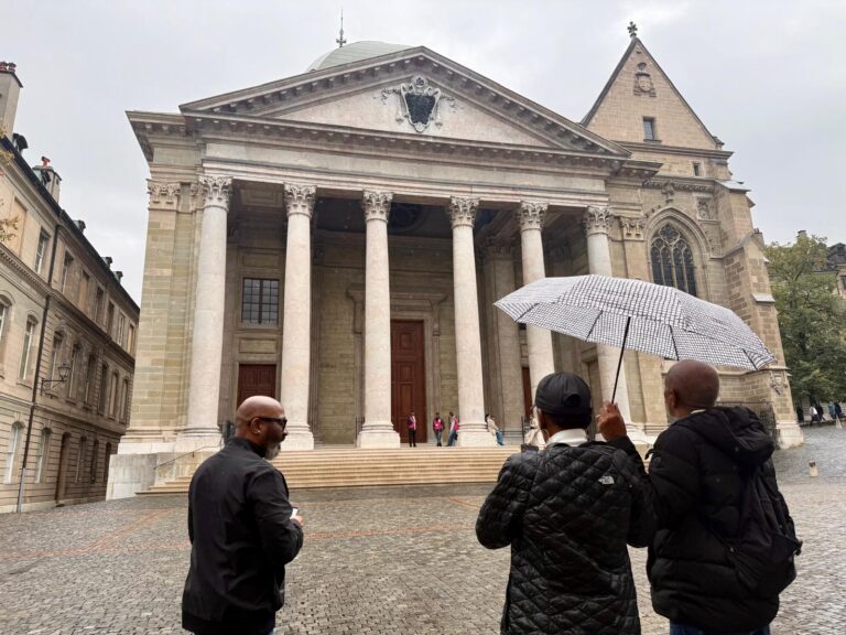 Visitors with an umbrella in front of a stone cathedral with tall columns
