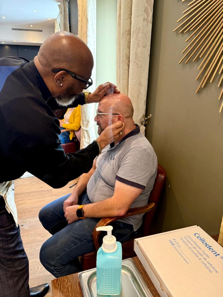 A trainer treating a seated participant’s ear